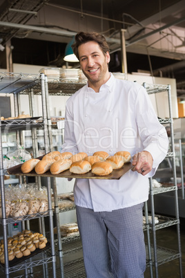 Happy baker showing tray with bread