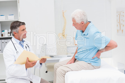 Doctor discussing reports with patient suffering from back pain