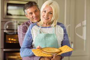 Mature blonde holding fresh pie with husband hugging her