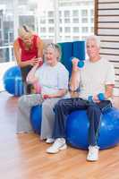 Trainer motivating senior couple in lifting dumbbells