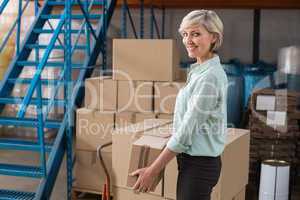 Smiling warehouse manager holding cardboard box