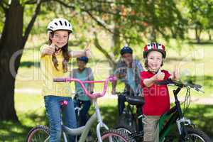 Happy family on their bike at the park with thumbs up
