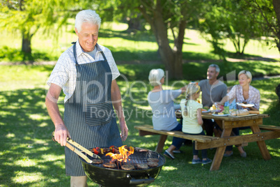 Happy grandfather doing barbecue