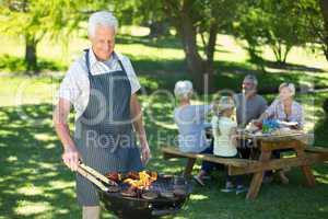 Happy grandfather doing barbecue