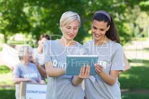 Happy volunteer friends using tablet pc