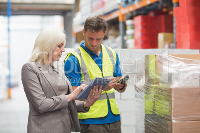 Manager using tablet while worker scanning package