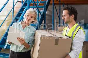 Warehouse manager and worker looking at clipboard