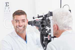 Happy optometrist examining senior patients eye