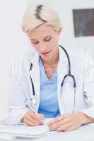 Doctor writing prescription at table