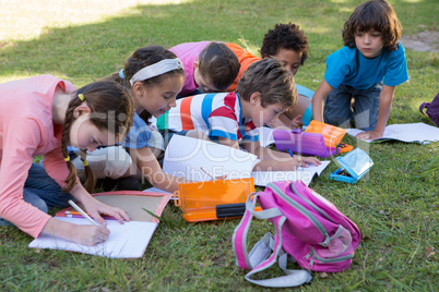School children doing homework on grass