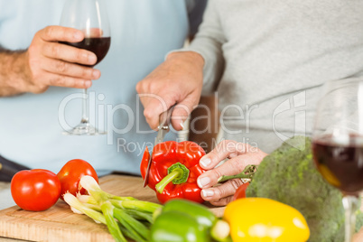 Mature couple having red wine while making dinner