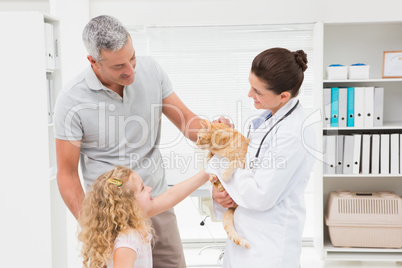 Veterinarian holding cat with its owners