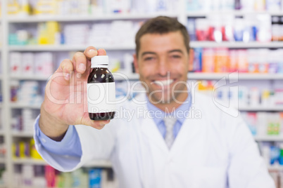 Handsome pharmacist showing medicine bottle