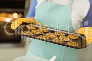 Woman showing tray of fresh cookies