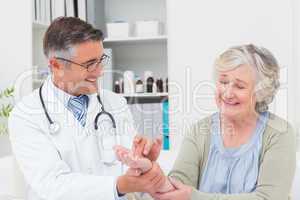 Male doctor examining patients hand at table