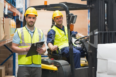 Smiling warehouse worker and forklift driver