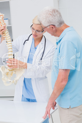 Orthopedic doctor and senior patient discussing over anatomical