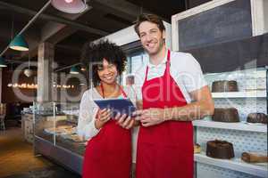 Happy co-workers in red apron holding tablet