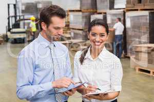 Smiling warehouse managers working together