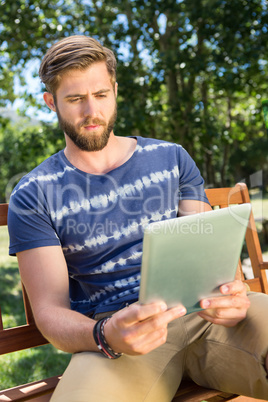 Young man using tablet on park bench