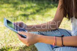 Pretty brunette using tablet in park