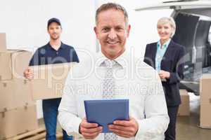 Smiling manager holding tablet in front of his colleagues