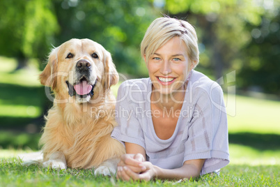 Happy blonde lying with her dog in the park