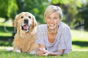 Happy blonde lying with her dog in the park