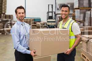 Warehouse worker and manager passing a box