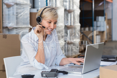 Smiling warehouse manager using laptop