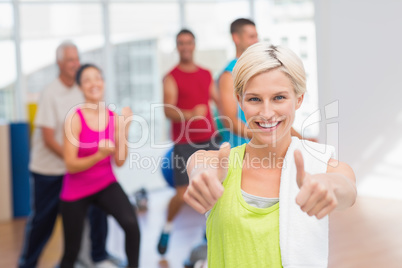 Happy woman gesturing thumbs up at gym