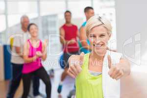 Happy woman gesturing thumbs up at gym