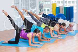 People exercising on fitness mats at gym