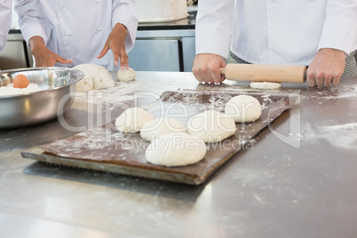 Colleagues kneading dough with rolling pin