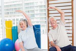 Senior couple doing stretching exercise in gym