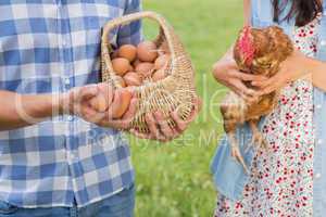 Happy farmers holding chicken and eggs