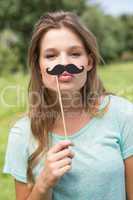 Pretty blonde smiling at camera with fake mustache