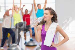 Tired woman drinking water at fitness club
