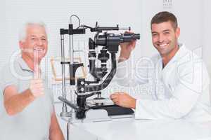 Senior man showing thumbs up while sitting with optician