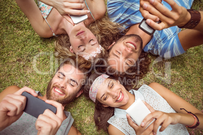 Hipsters lying on grass using smartphones