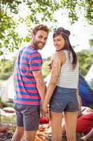 Hipster couple holding hands on campsite