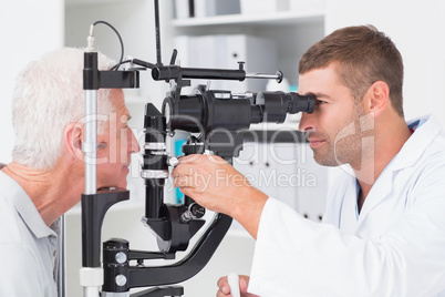 Optometrist examining senior patients eyes through slit lamp