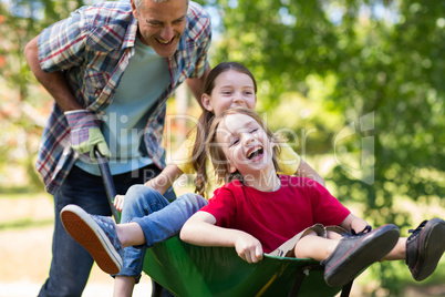 Happy father and his children playing with a wheelbarrow Happy father and his children playing with a wheelbarrow