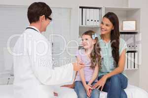 Doctor examining little girl with her mother