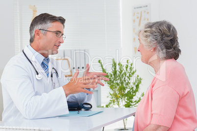 Male doctor conversing with female patient at table