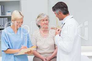 Doctor consoling patient while nurse writing reports