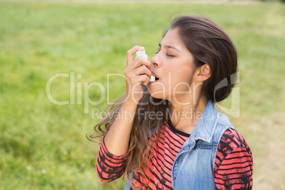 Pretty brunette using her inhaler