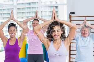 Happy friends practicing tree pose in fitness studio