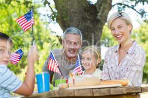 Happy family having picnic and holding american flag