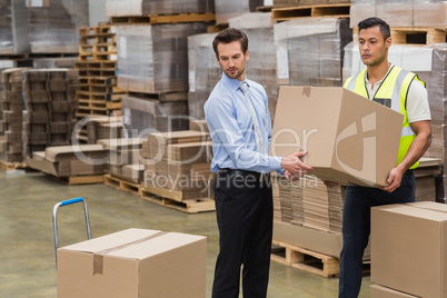 Warehouse worker and manager carrying a box together